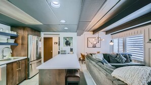 A modern kitchen with a central island, wooden cabinets, and a stainless steel refrigerator. - The Lift B107 2 Bedroom Condo (Breckenridge)