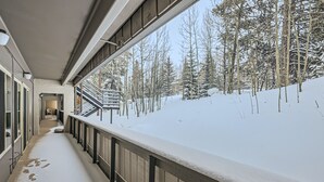 A snow-covered balcony with a view of a forested area. - The Lift B107 2 Bedroom Condo (Breckenridge)