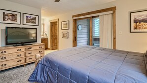 A bedroom with a bed, a TV, wooden furniture, and framed pictures on the wall.