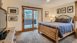 A bedroom with a wooden bed, a ceiling fan, and a sliding glass door leading to an outdoor area.
