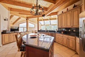 Une cuisine spacieuse avec des meubles en bois, un grand îlot central et un lustre.