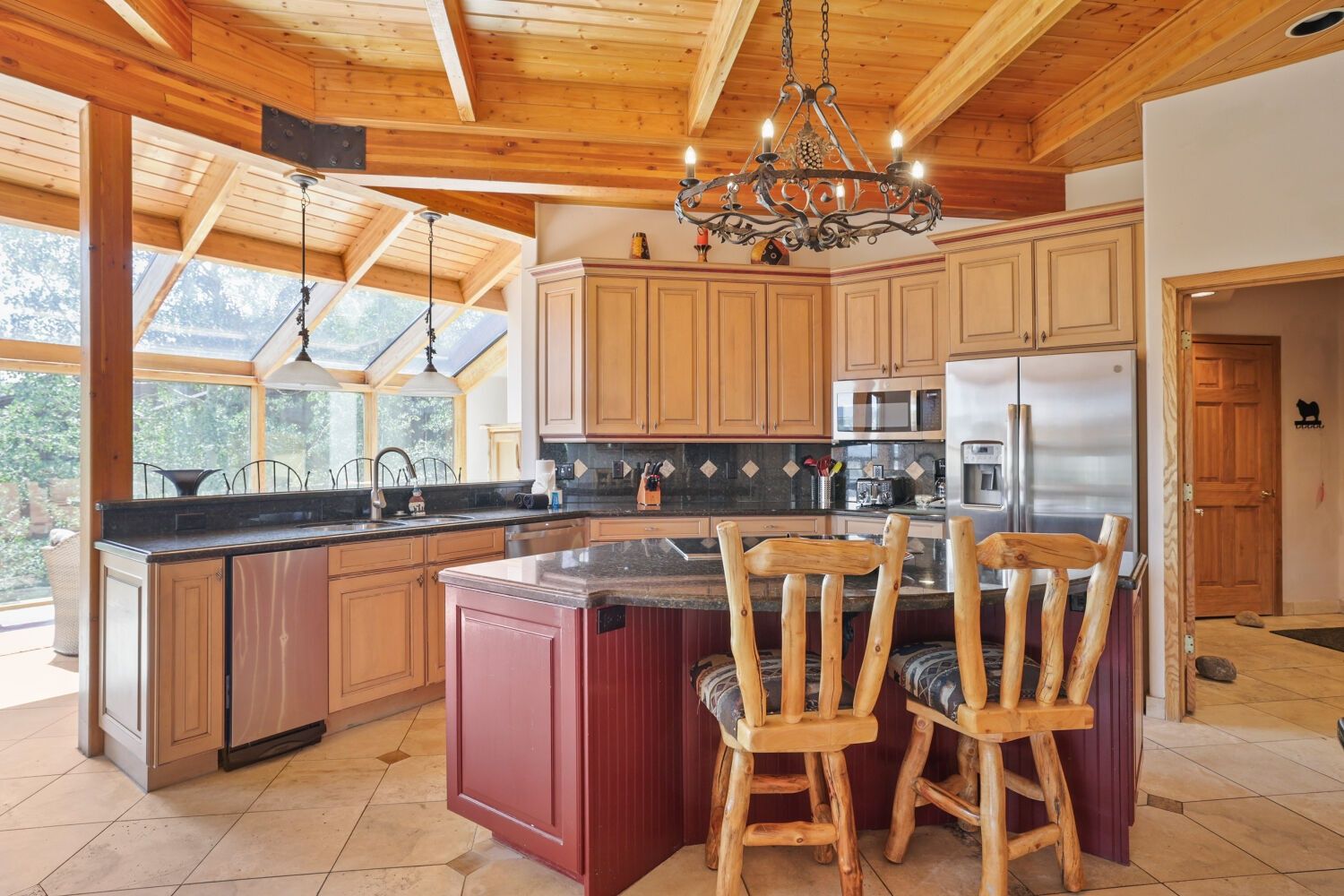 A spacious kitchen with wooden cabinets, a central island, and a chandelier.