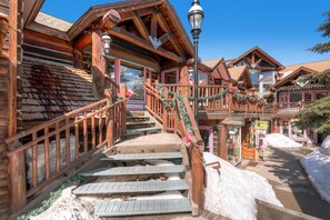 Un edificio de madera con una escalera que conduce a un balcón, rodeado de nieve.