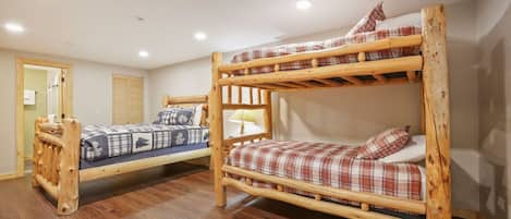Ein Zimmer mit zwei Etagenbetten, Holzboden und einer Tür zu einem Badezimmer.