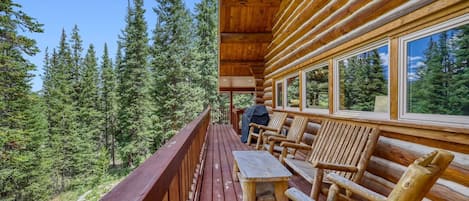 Une terrasse en bois avec une table et des chaises, donnant sur une zone boisée.