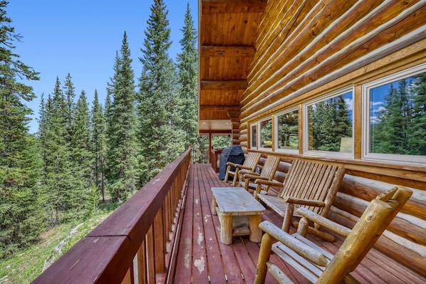 Une terrasse en bois avec une table et des chaises, donnant sur une zone boisée.