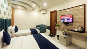 A hotel room with two beds, a TV mounted on the wall, a small refrigerator, and a coffee maker on the counter. - Hotel Lotus Arc (New Delhi)