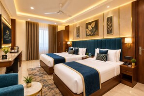 A hotel room with two beds, a desk, a chair, a small table, and a ceiling fan. - Hotel Lotus Arc (New Delhi)