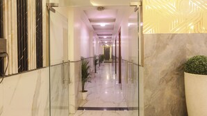 A hotel lobby with a marble floor, a glass railing, potted plants, and a 'WELCOME' sign. - Hotel Lotus Arc (New Delhi)