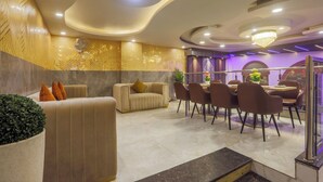 A modern hotel lobby with a seating area, a dining table, and a chandelier. - Hotel Lotus Arc (New Delhi)