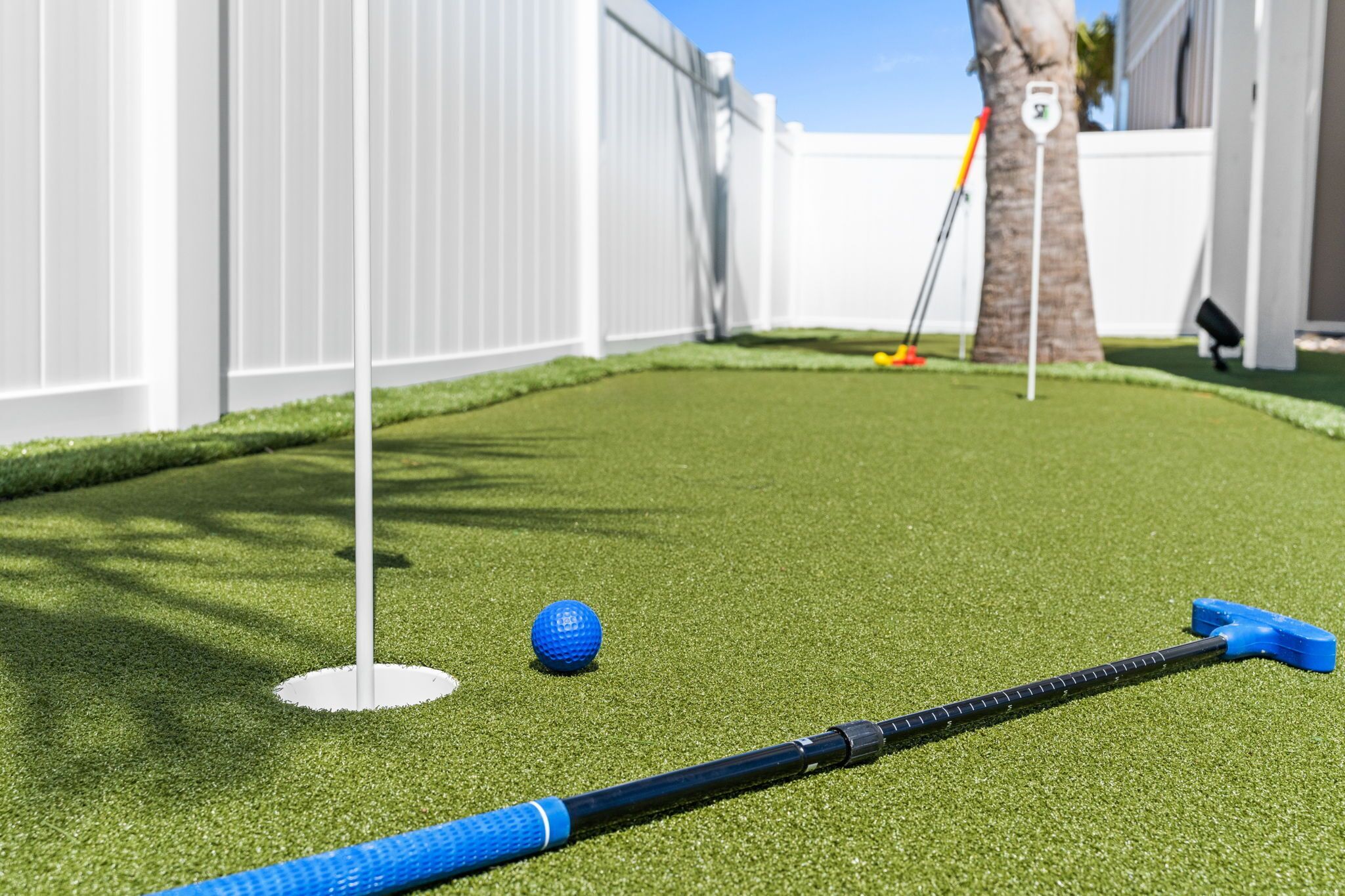 A miniature golf course with a blue ball, a putter, and a golf club.