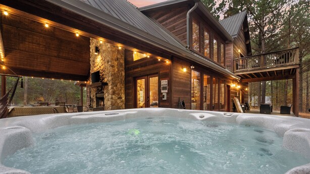 Ein Bereich mit Whirlpool, Steinwand, Holzterrasse und Lichterkette.