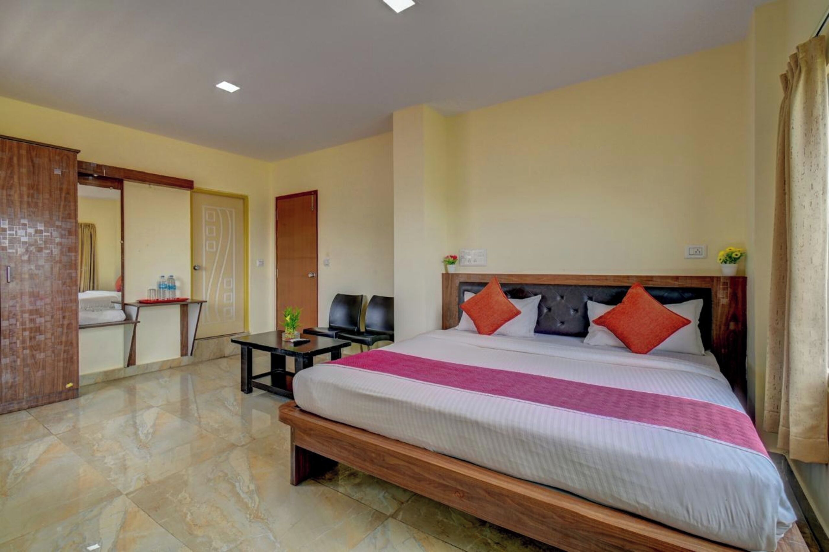 A hotel room with a large bed, a wooden headboard, and a small table with chairs.