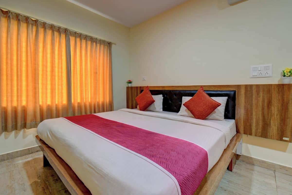 Une chambre d’hôtel avec un grand lit, une tête de lit en bois et une fenêtre avec des rideaux.