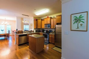 A modern kitchen with wooden cabinets, stainless steel appliances, and a central island. - Low Country Dawg House | Stunning Walking Trails! (Athens)