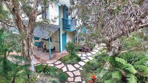 A house with a blue exterior, a stone pathway, and a garden with various plants and a bench.