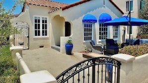 A house with a tiled roof, a gated entrance, and outdoor furniture.