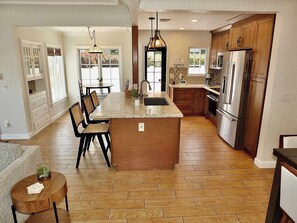 Una cocina amplia con una isla central, armarios de madera y un comedor con sillas.