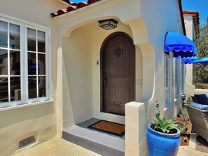 Una casa con una puerta de madera grande, una ventana y un toldo azul.