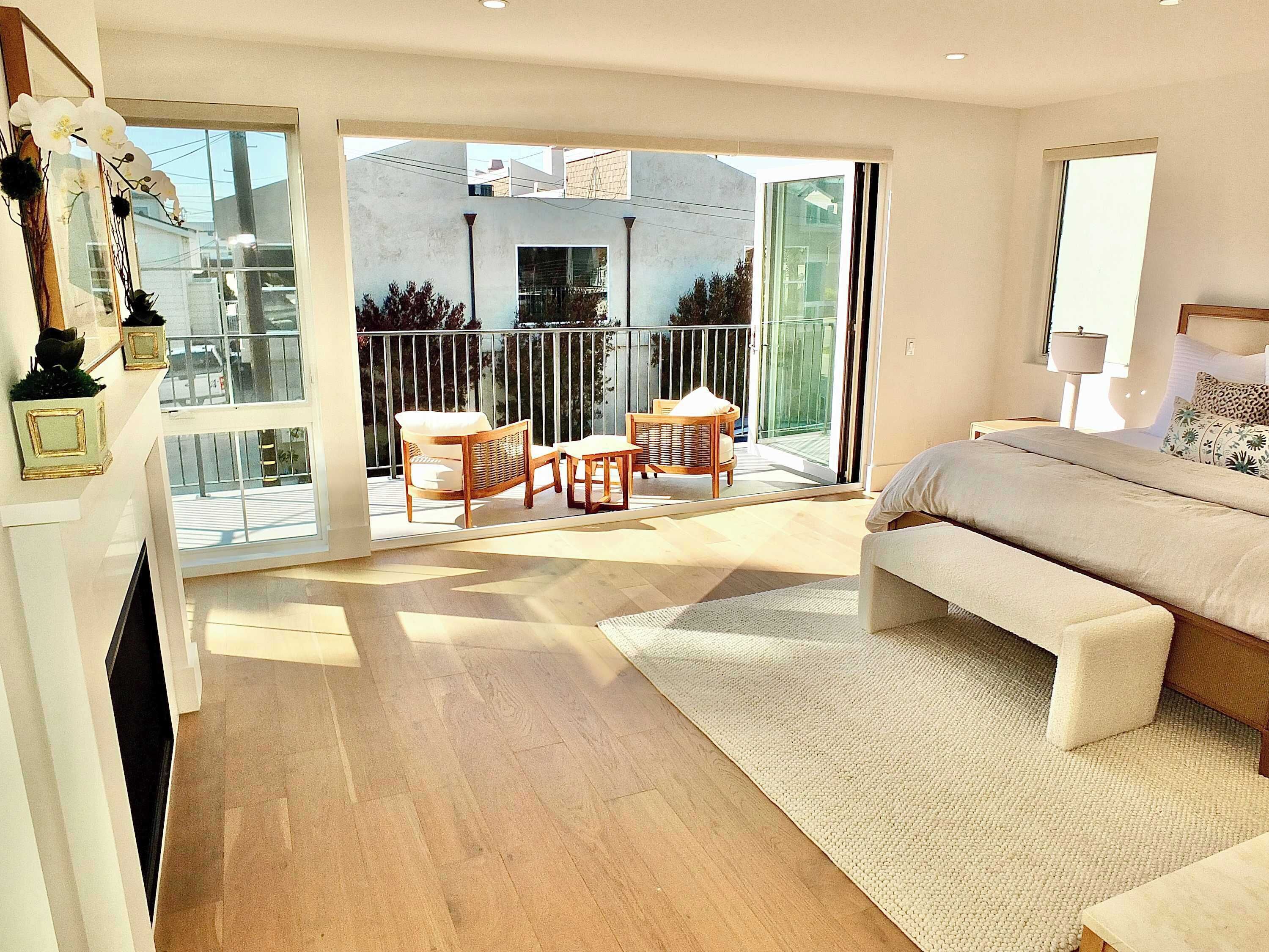 Ein modernes Schlafzimmer mit einem großen Bett, einer Couch und einem Balkon mit Korbmöbeln.