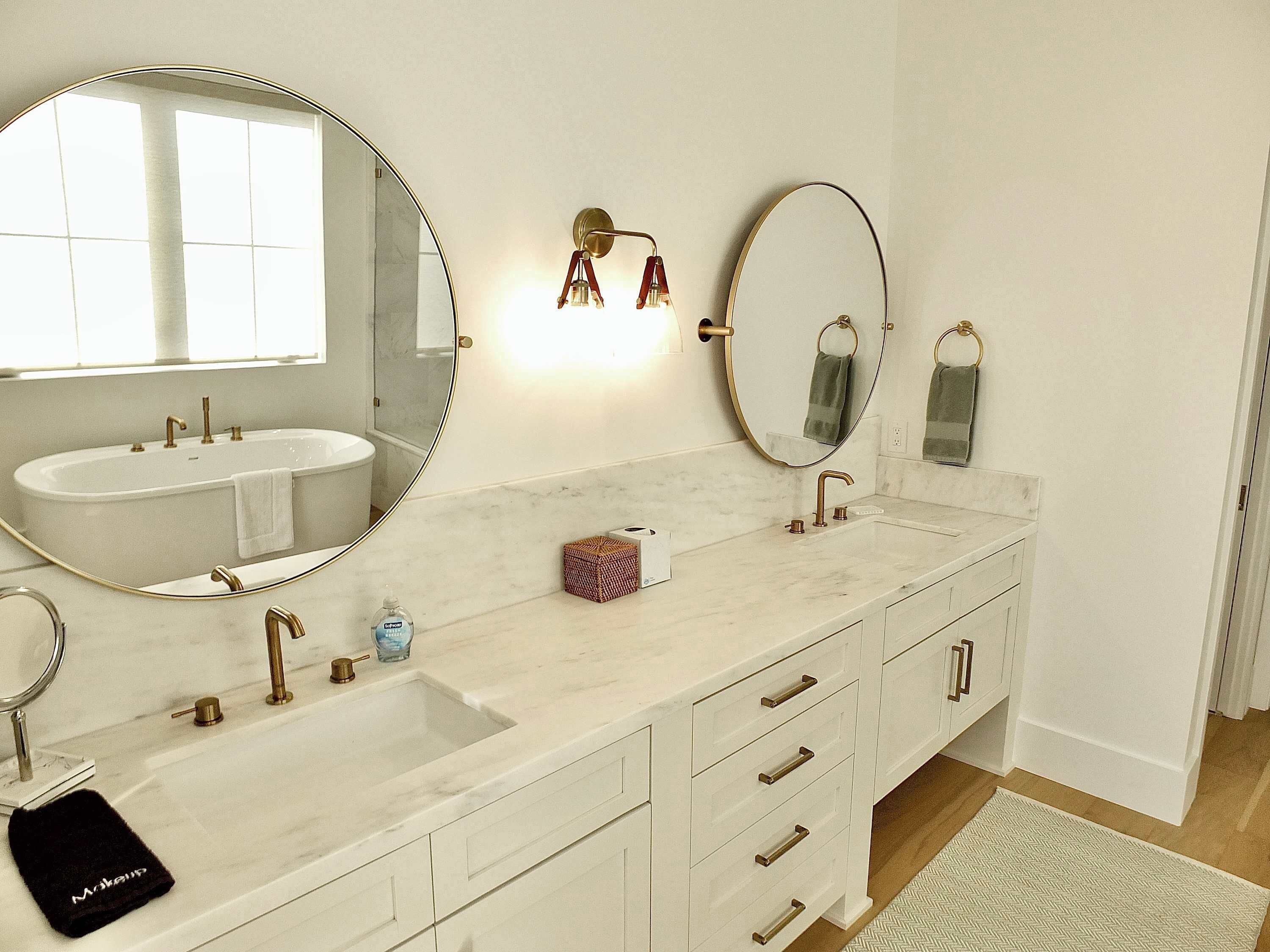 Une salle de bain avec deux lavabos, un grand miroir et un meuble-lavabo avec des tiroirs.