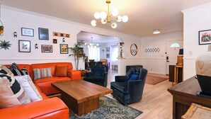 Una sala de estar moderna con una mesa de centro de madera, sofás naranja y negros, y una araña.