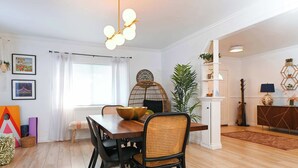 Un comedor con una mesa de madera, sillas negras, una silla de mimbre, una lámpara colgante y una planta.