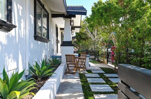 A modern house with a white exterior, a stone pathway, and a wooden bench.