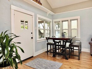 Una habitación con una mesa de comedor, sillas, una planta en maceta y una puerta.