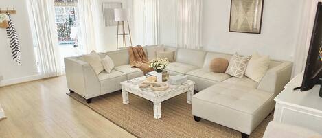 A living room with a sectional sofa, a coffee table, and a television.