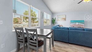 Una sala de estar moderna con comedor, ventanas amplias, ventilador de techo y televisor.