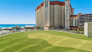 Un campo de golf con vista a un hotel y al océano al fondo.