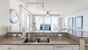 A modern kitchen with granite countertops, a double sink, and a view to the outside.