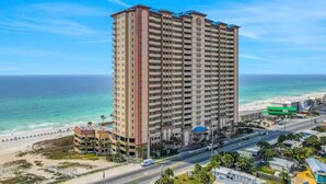 Un hotel moderno de gran altura con varias plantas, vista al mar y una carretera con vehículos.