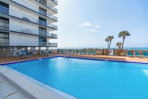 A swimming pool with lounge chairs and a view of the ocean.