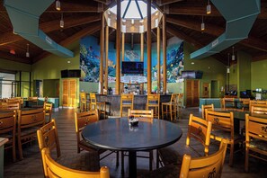 A restaurant with wooden tables and chairs, a bar area, and a mural of an underwater scene on the wall.