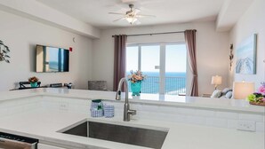 A modern kitchen with a large island, a built-in sink, and a ceiling fan. - Sandy Feet Retreat | Ocean View, Beach Access | Activity Deals (Panama City Beach)
