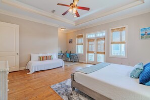 Ein Schlafzimmer mit zwei Betten, einem Deckenventilator und einem Schreibtisch mit Stuhl.
