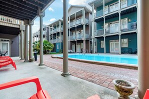 Un edificio de varios pisos con piscina, mobiliario exterior y un patio cubierto.