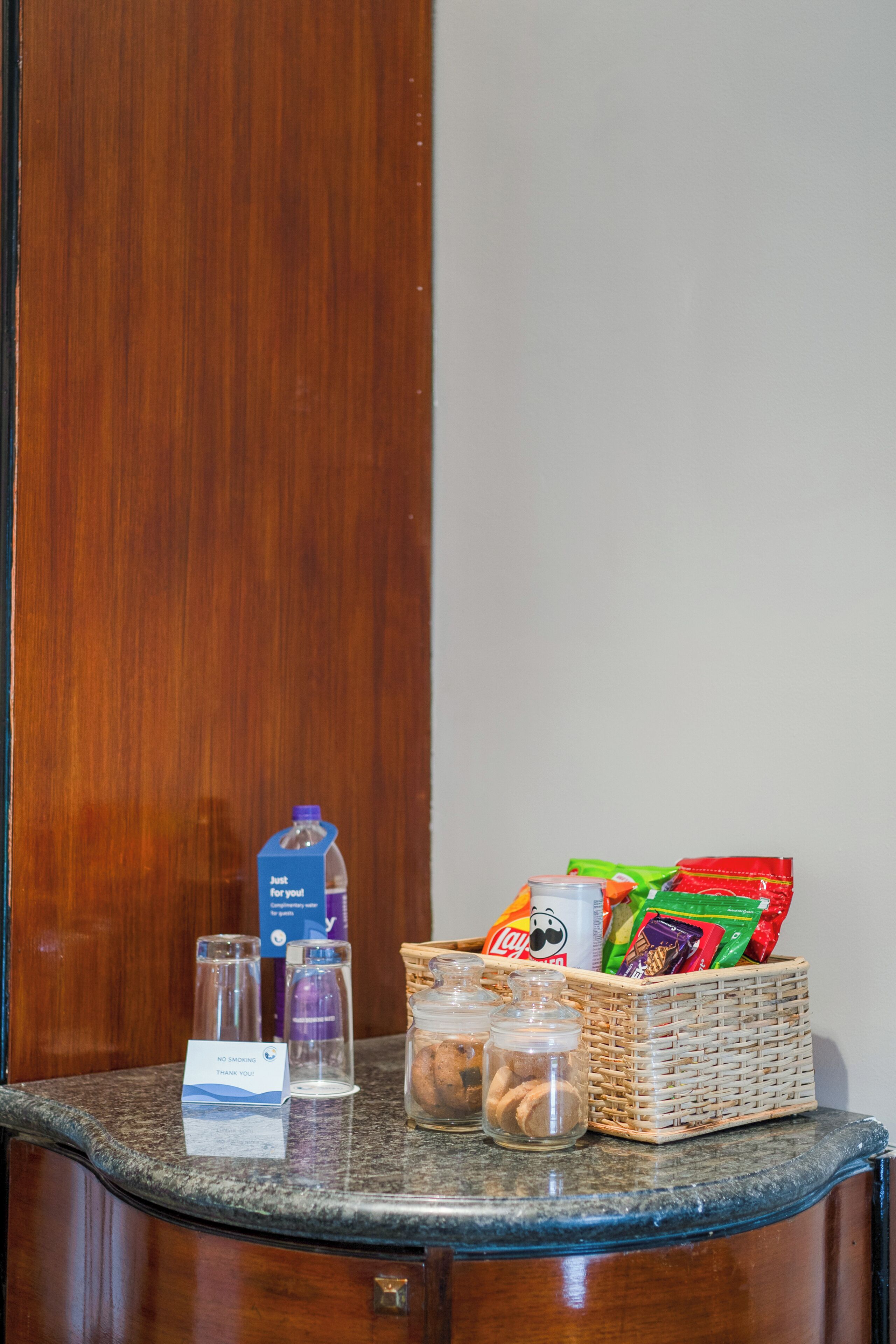 A small counter with a basket of snacks, a bottle of water, and a 'No Smoking' sign.