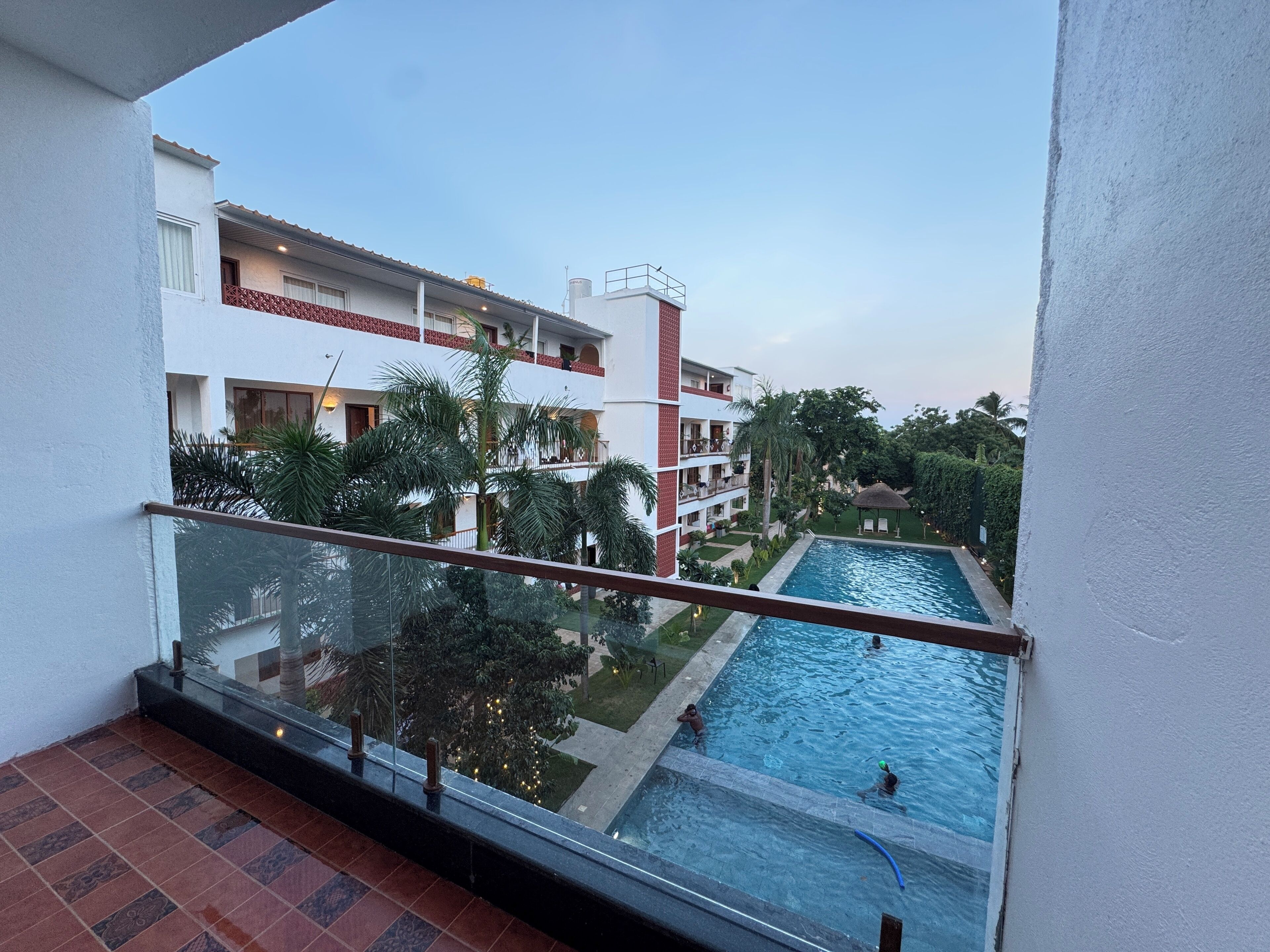 Un hotel con piscina, varios pisos y vistas a la vegetación circundante.