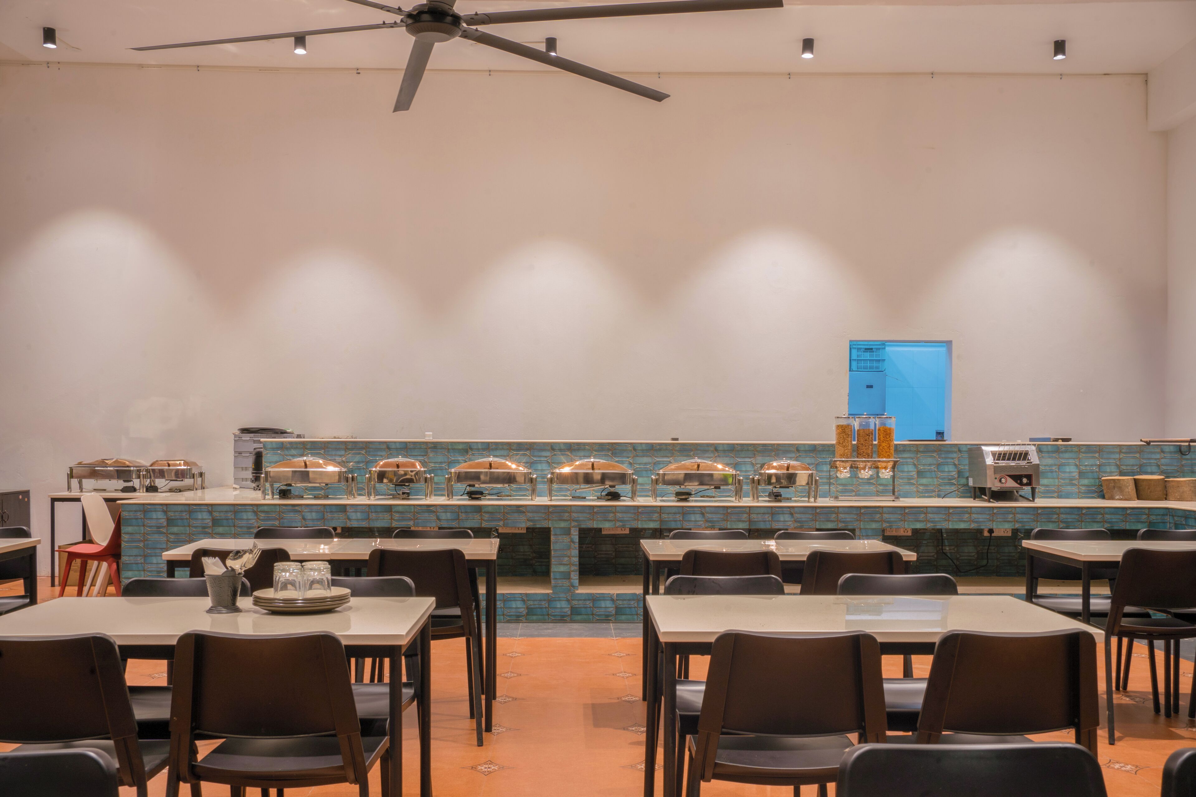 A buffet-style restaurant with multiple serving stations, a ceiling fan, and a tiled backsplash.