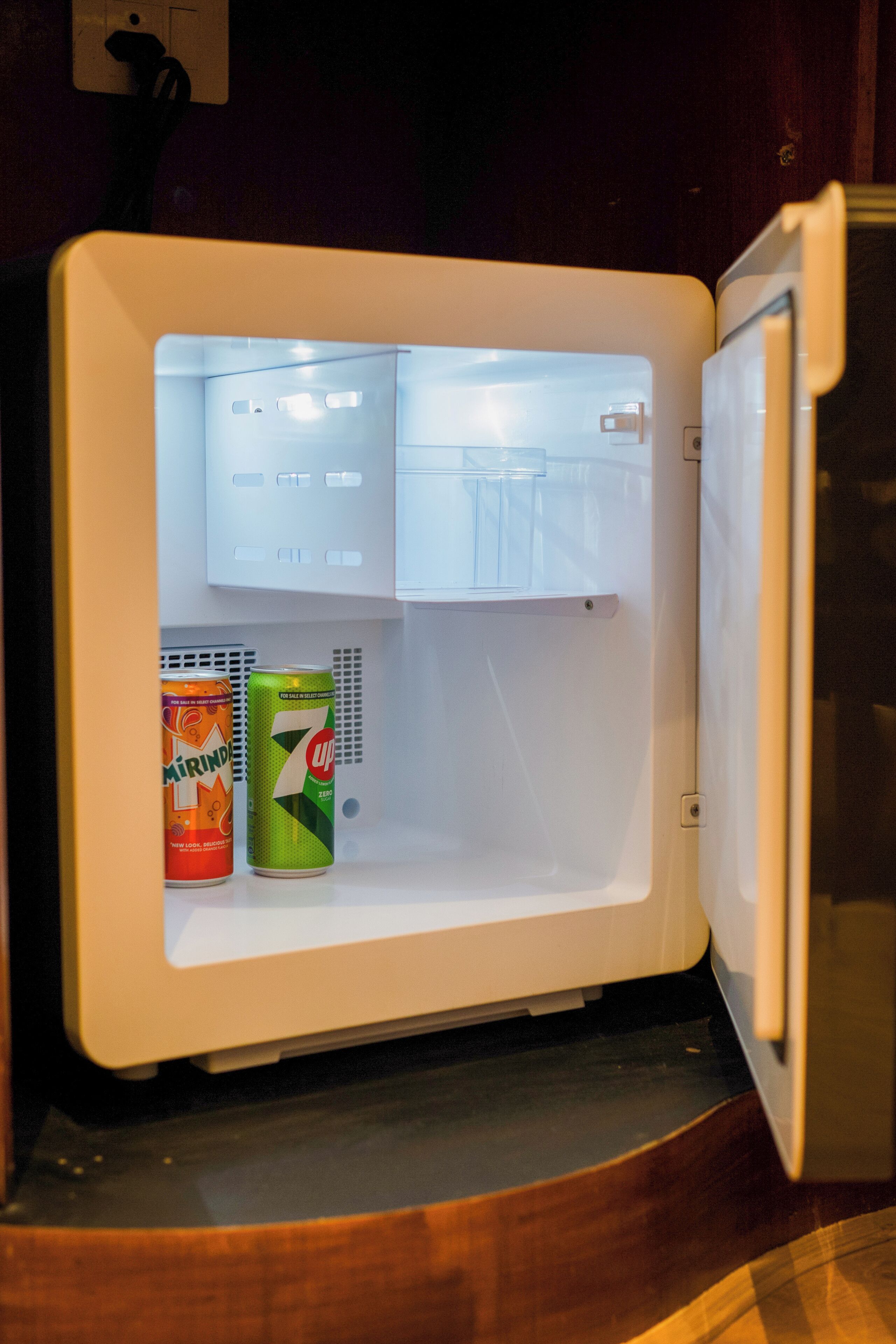 A compact refrigerator with two beverage cans inside.