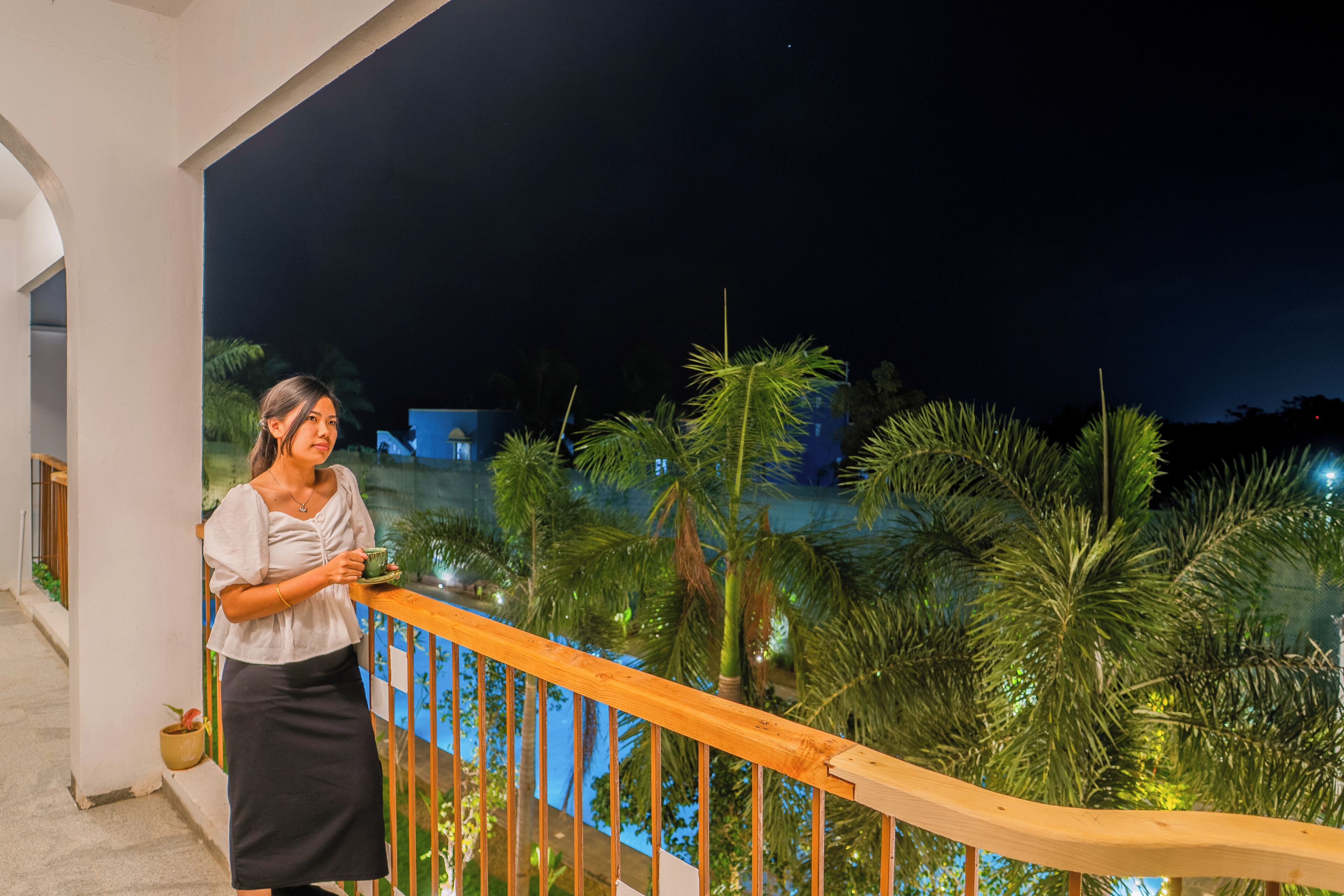 Ein Balkon mit Holzgeländer, der auf einen Poolbereich mit Palmen blickt.