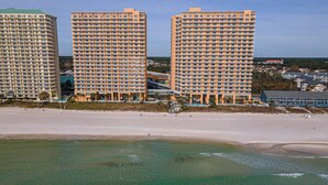 Un hotel frente a la playa con varios edificios altos, una playa de arena y una vista despejada del océano.