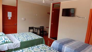 A room with two beds, a ceiling fan, a TV mounted on the wall, and a small table with chairs.