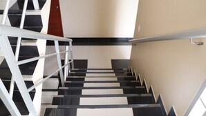 A staircase with black and white steps, white handrails, and a beige wall. - Hotel Virrey (San Ramón)