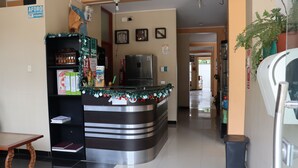 A reception area with a curved counter, a refrigerator, and a trash bin. - Hotel Virrey (San Ramón)