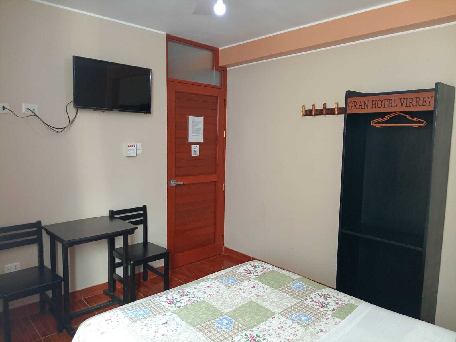 A hotel room with a bed, a desk, a chair, a television, and a wardrobe.