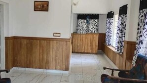 Ένας χώρος υποδοχής με έναν ξύλινο πάγκο υποδοχής, έναν πίνακα με κορνίζα στον τοίχο και κουρτίνες με σχέδια.